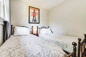 Un lit double avec une couvre-lit à motifs, une table de chevet avec une lampe et une affiche accrochée au mur.