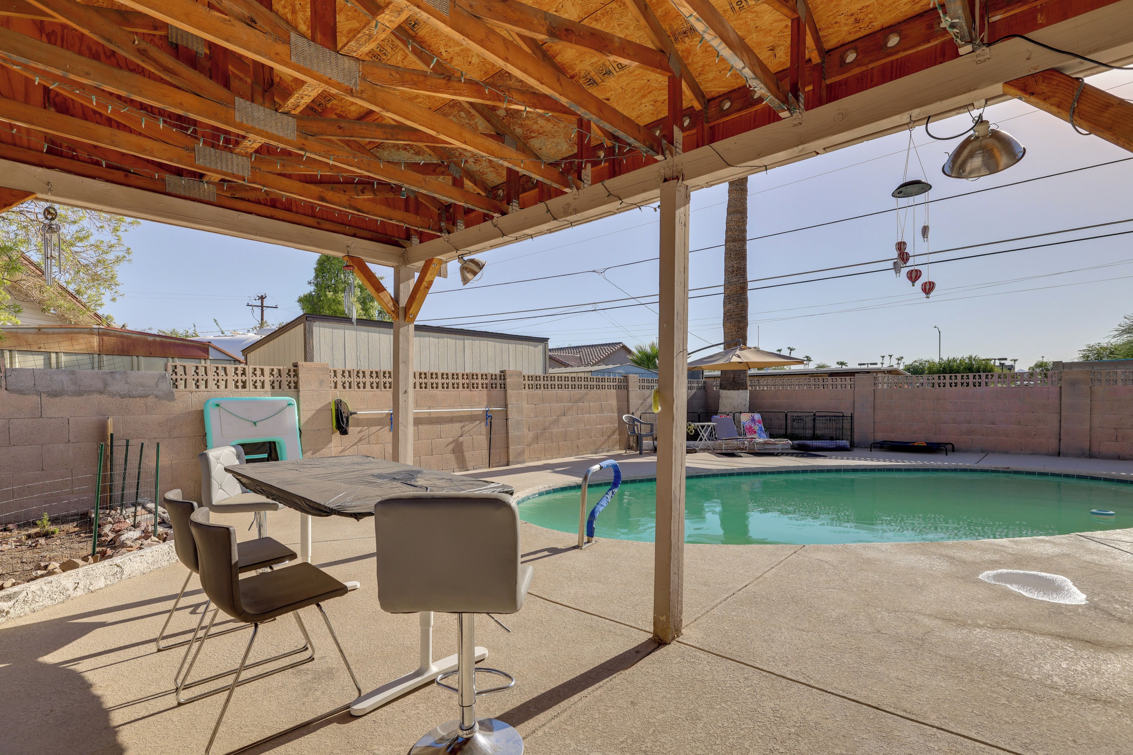 A covered outdoor area with a pool, a table, and chairs.