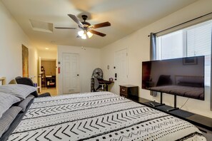 Ein Schlafzimmer mit einem Bett, einem Deckenventilator, einem Fernseher und einem Fenster mit Jalousien.