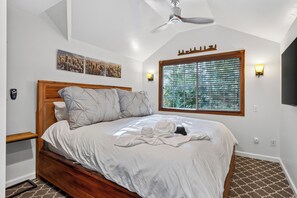Ein Schlafzimmer mit einem hölzernen Bett, einem Deckenventilator, einem Fenster mit Jalousien und Wandleuchten.