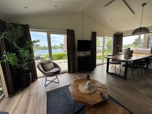 Una sala de estar moderna con un gran ventanal, comedor y televisor de pantalla plana.
