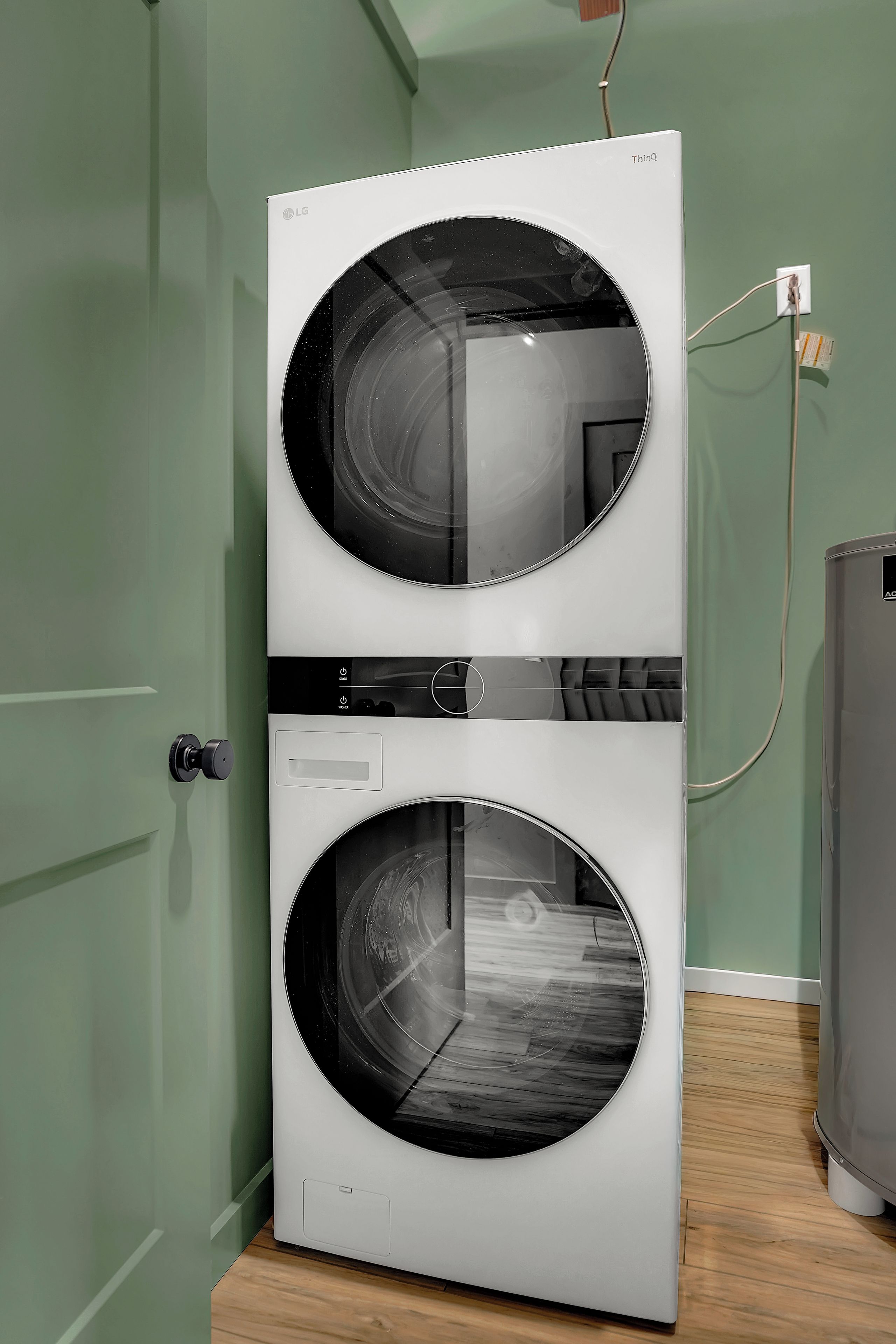 A front-loading LG ThinQ washer and dryer unit with a control panel and a power cord plugged into a wall outlet.