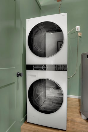 A front-loading LG ThinQ washer and dryer unit with a control panel and a power cord plugged into a wall outlet.