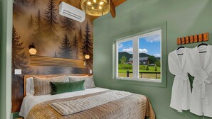 Un dormitorio con una cama grande, un ventanal con vista a una casa y una pared con un mural de un bosque.