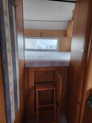 Un intérieur de camping-car compact comprenant un lit superposé, une petite table et une fenêtre.