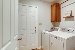 A laundry room with a white door, a wooden cabinet, and two white washing machines.