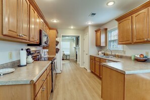 A kitchen with wooden cabinets, a refrigerator, a microwave, and a sink.