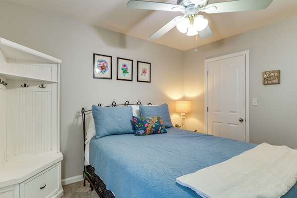 A bedroom with a bed, a nightstand, a lamp, and a ceiling fan.