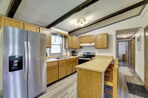 A modern kitchen with wooden cabinets, stainless steel appliances, and a central island. - Deck, Public Lake Access, Mountain Getaway (Equinunk)