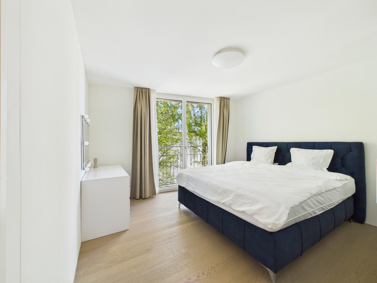 A bedroom with a bed, a bedside table, and a window with curtains.
