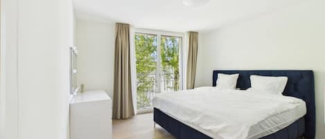 A bedroom with a bed, a bedside table, and a window with curtains.