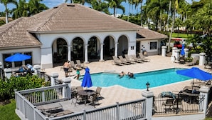 Un resort con piscina, sillas de descanso y palmeras.