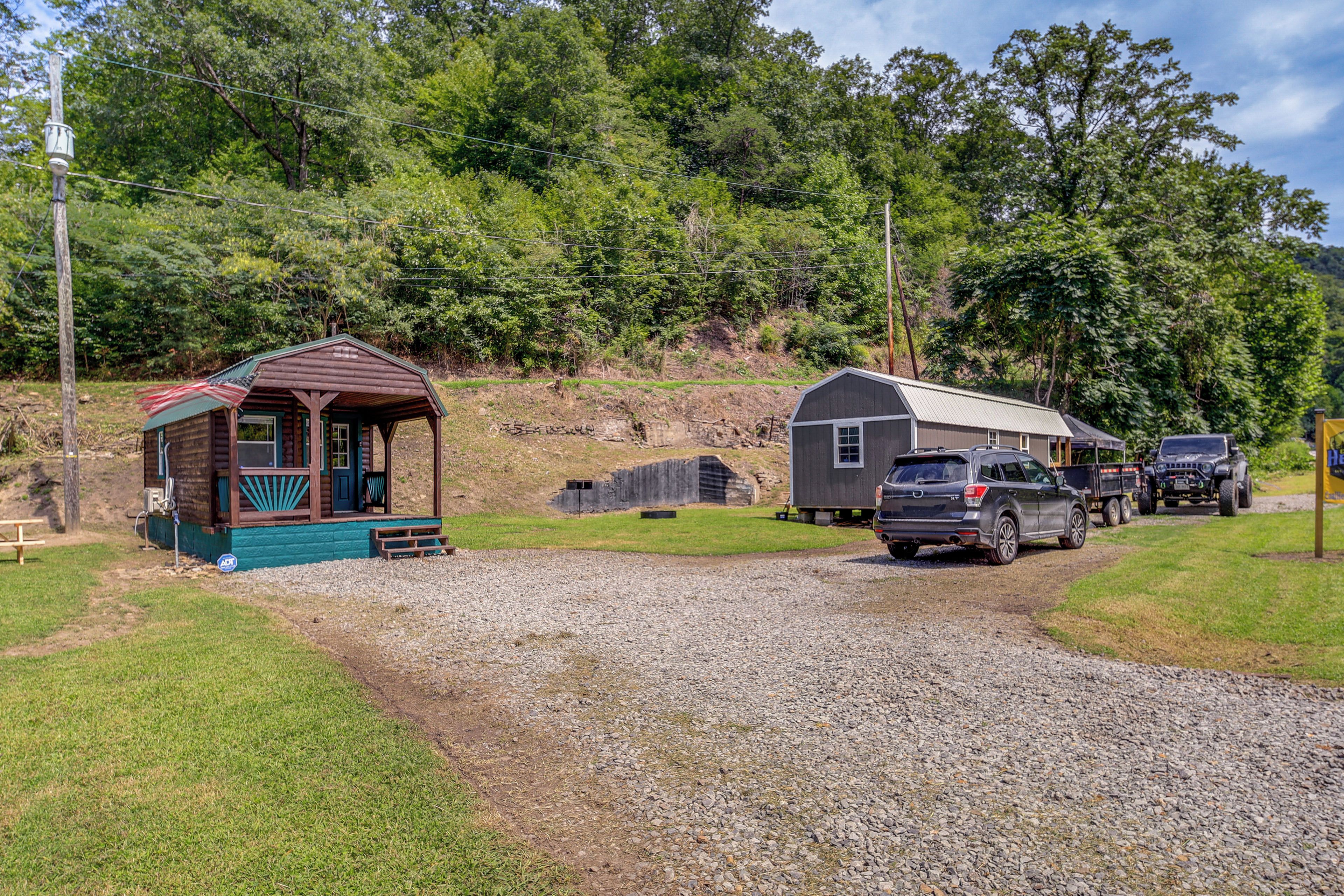 A gravel driveway leading to a cabin with a porch and a small shed nearby.