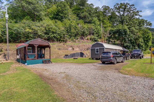 A gravel driveway leading to a cabin with a porch and a small shed nearby.