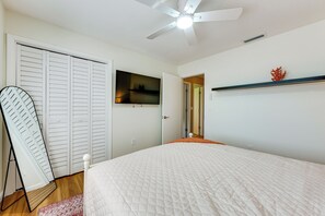 A bedroom with a bed, a ceiling fan, a TV, a wardrobe, and a shelf with a decorative item. - 2 Mi to Redington Beach! Tropical Poolside Retreat (Seminole)