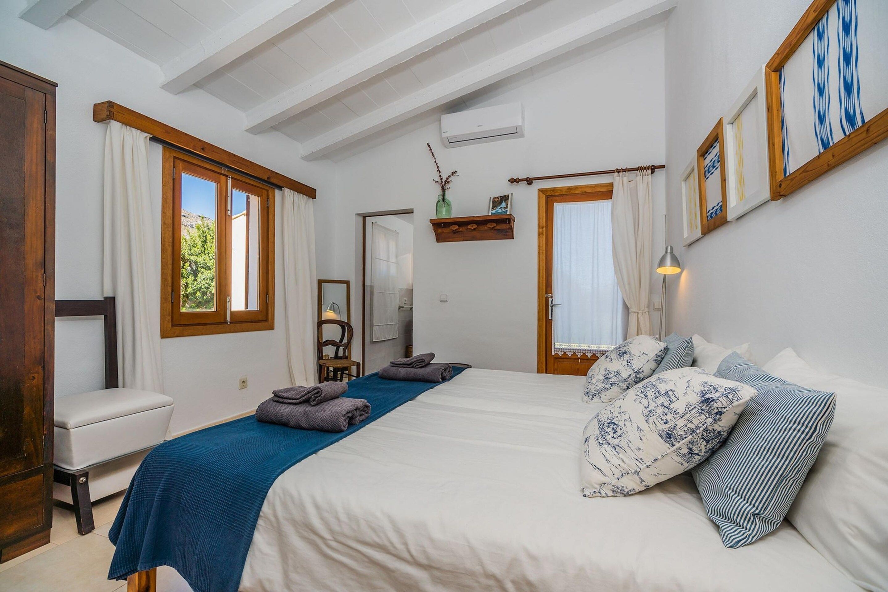 A bedroom with a bed, a chair, a desk, and a window.
