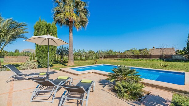 A swimming pool with lounge chairs and an umbrella, surrounded by greenery and a clear sky. - Idyllic Country Getaway for 2 (Pollença)