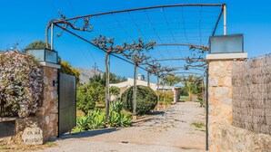 A gravel driveway leading to a stone gate with a metal fence overhead. - Idyllic Country Getaway for 2 (Pollença)