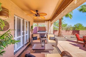 A covered patio area with wicker furniture, a ceiling fan, and a view of the outdoors. - Resort-Style Goodyear Home: Swim, Soak & Play! (Goodyear)