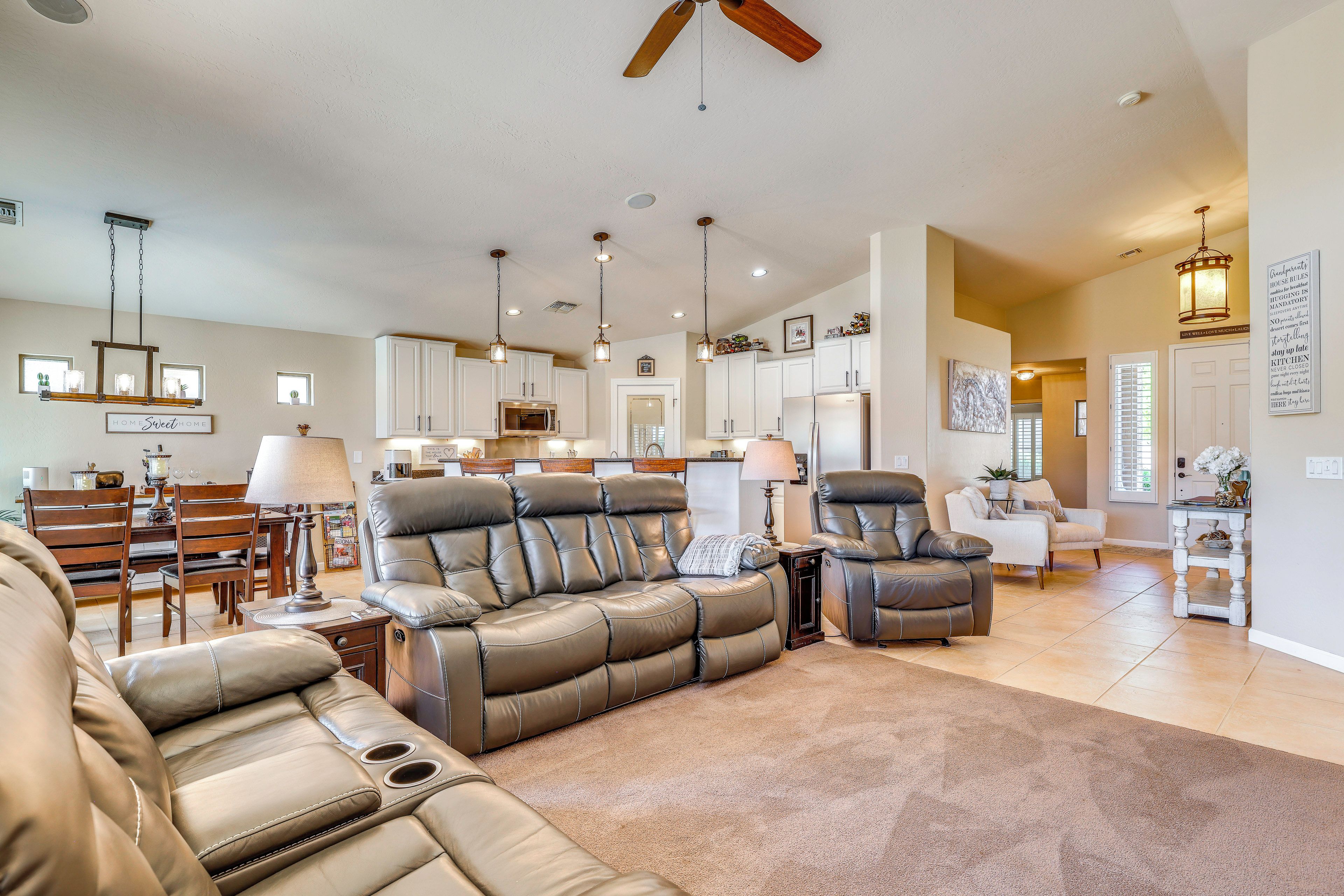 A spacious living room with a sectional sofa, a dining area with a wooden table, and a kitchen with white cabinets.