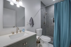 Un bagno con lavandino bianco, specchio e doccia con tenda blu.