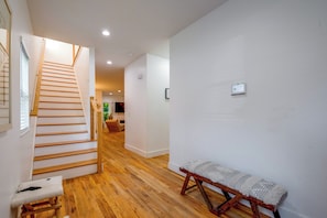 A modern interior with a wooden staircase, a bench, and a flat-screen TV mounted on the wall. - Upper Westside Home w/ Deck - 3 Mi to Dtwn! (Atlanta)