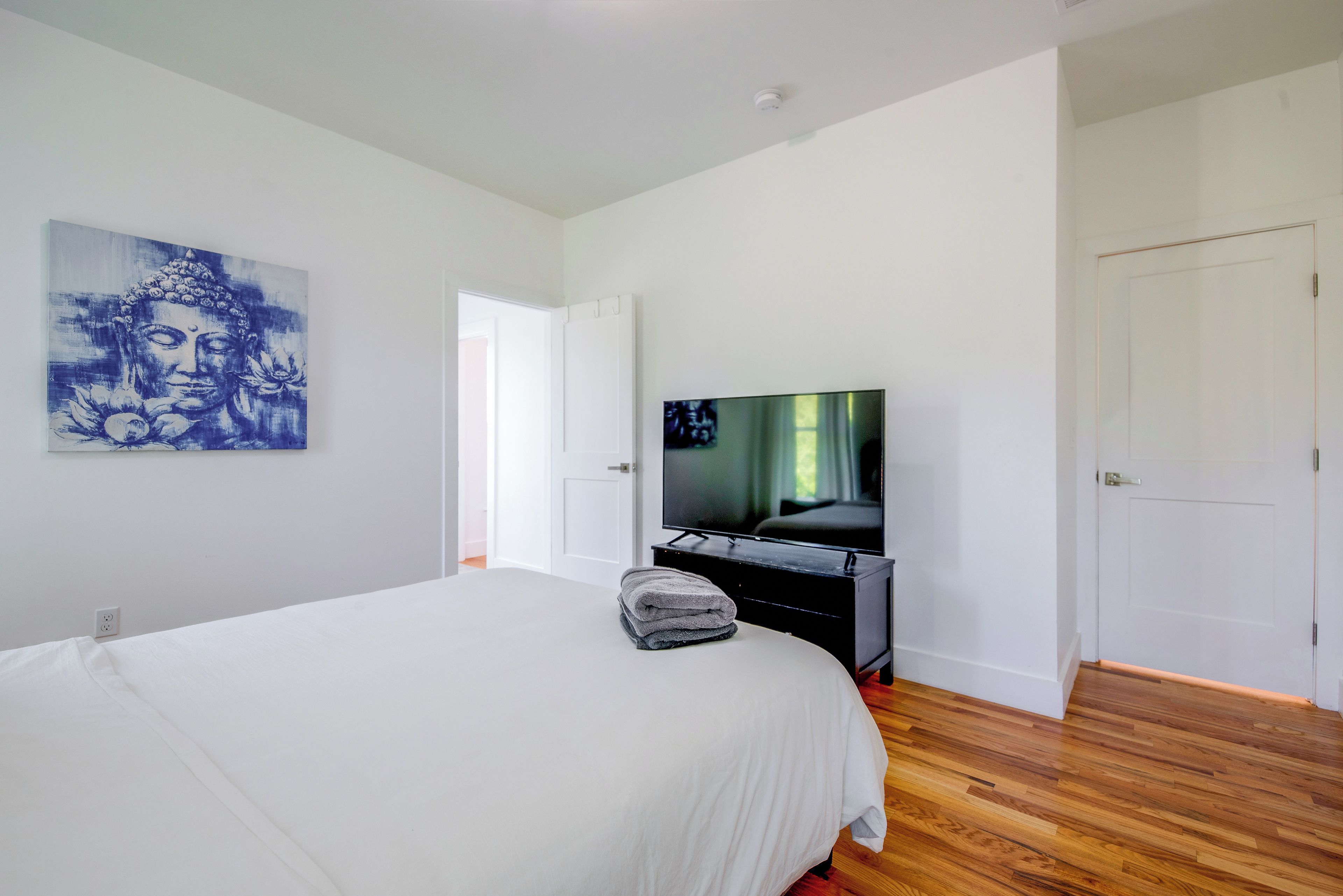Une chambre avec un grand lit, une télévision et un tableau accroché au mur.