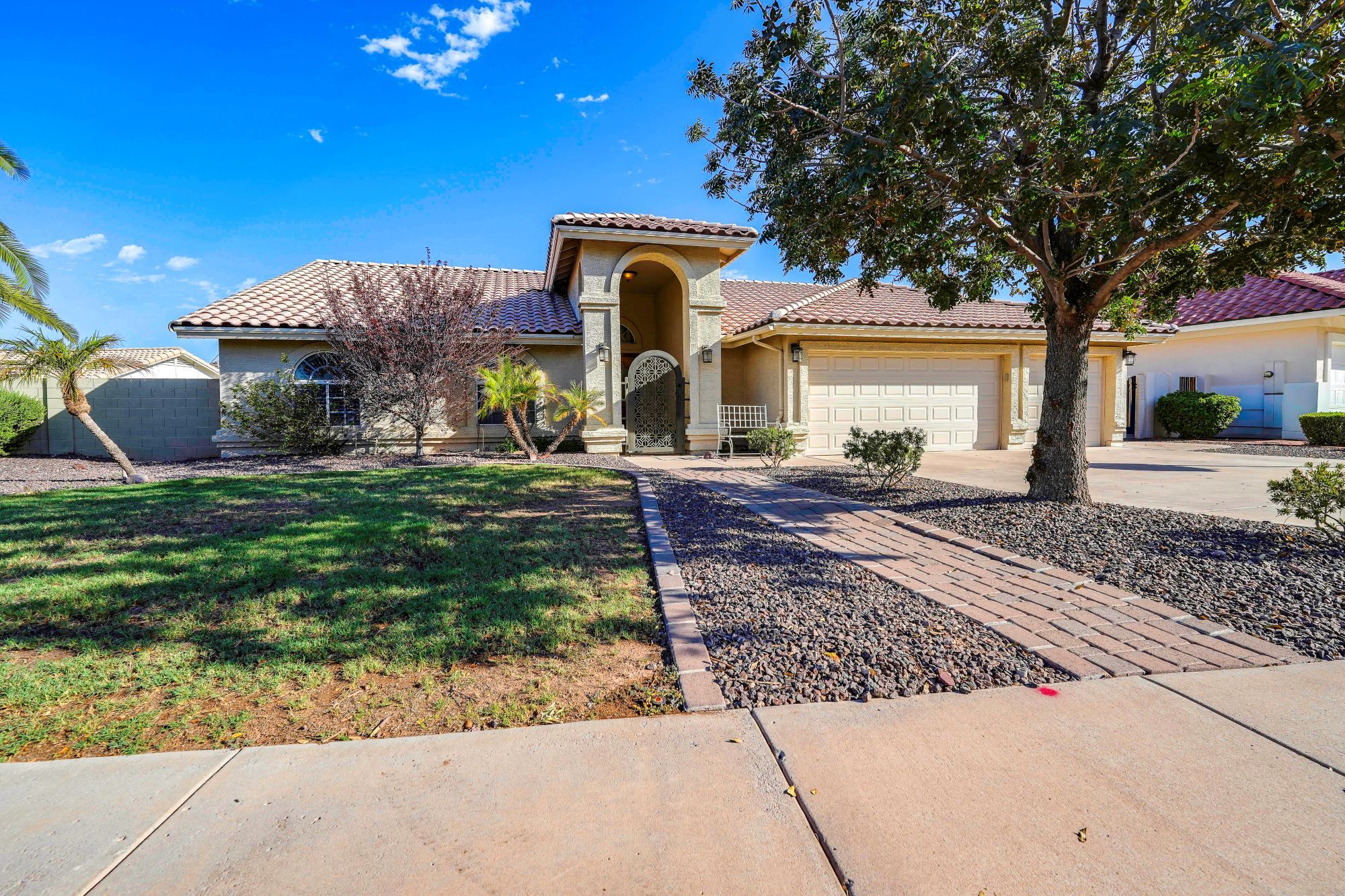 A residential house with a tiled roof, a driveway, and a well-maintained lawn.