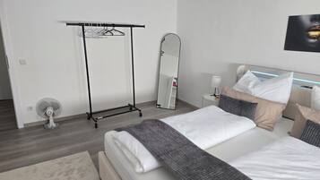 Quarto de hotel moderno com cama, mesa de cabeceira, abajur e espelho de corpo inteiro.