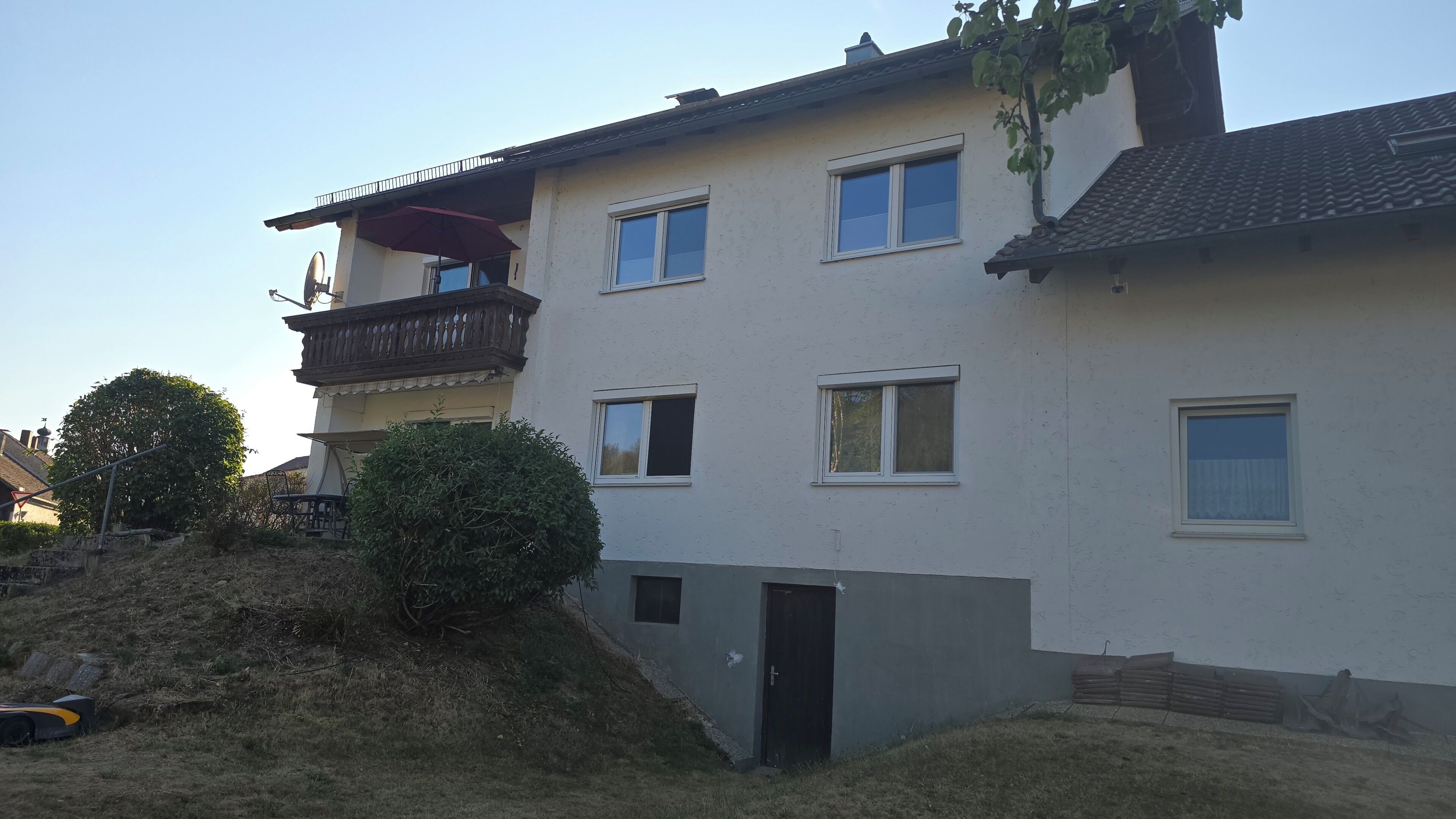 Ein mehrgeschossiges Wohnhaus mit Balkon, Fenstern und einer Tür.