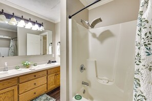 A bathroom with a wooden vanity, a mirror, a shower with a handheld showerhead, and a towel rack. - Fishing Dock & Sauna! Farmville Gem w/ Views (Farmville)
