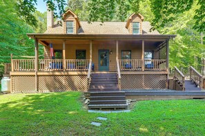 A two-story wooden house with a front porch, a front door, and a staircase leading to the entrance.