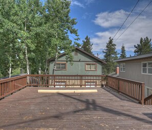A wooden deck leading to a cabin with a green exterior and a brown roof, surrounded by trees. - Aspen Glen Mountain Escape (Green Valley Lake)