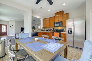 A modern kitchen with wooden cabinets, a built-in microwave, and a stainless steel refrigerator. - Kyle Home at Plum Creek Golf Course (Kyle)