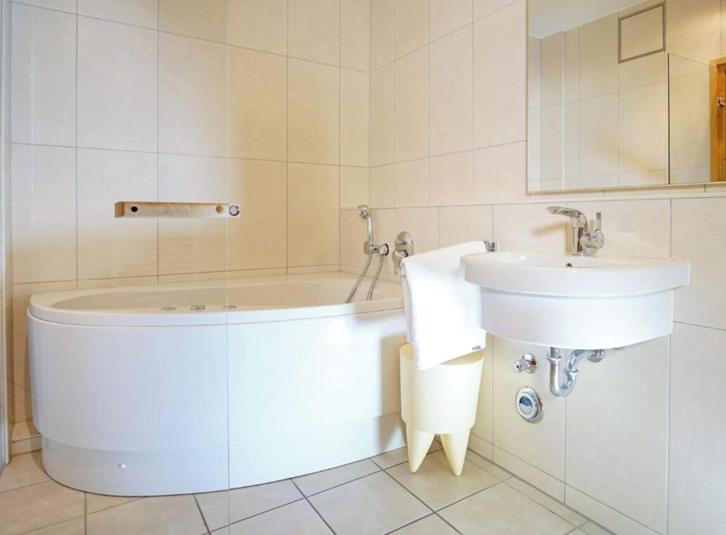 Ein modernes Badezimmer mit einer freistehenden Badewanne, einem Waschbecken und einem Spiegel.