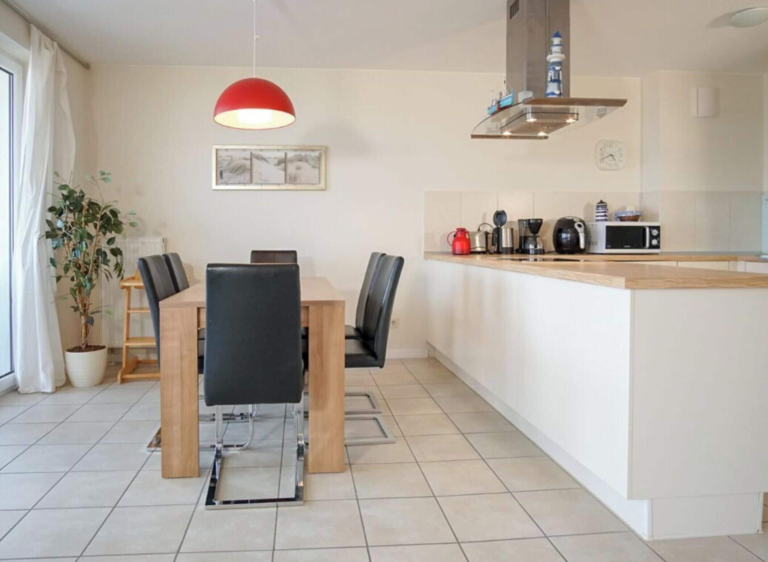 A modern kitchen with a central island, a dining area with a table and chairs, and a pendant light above the island.