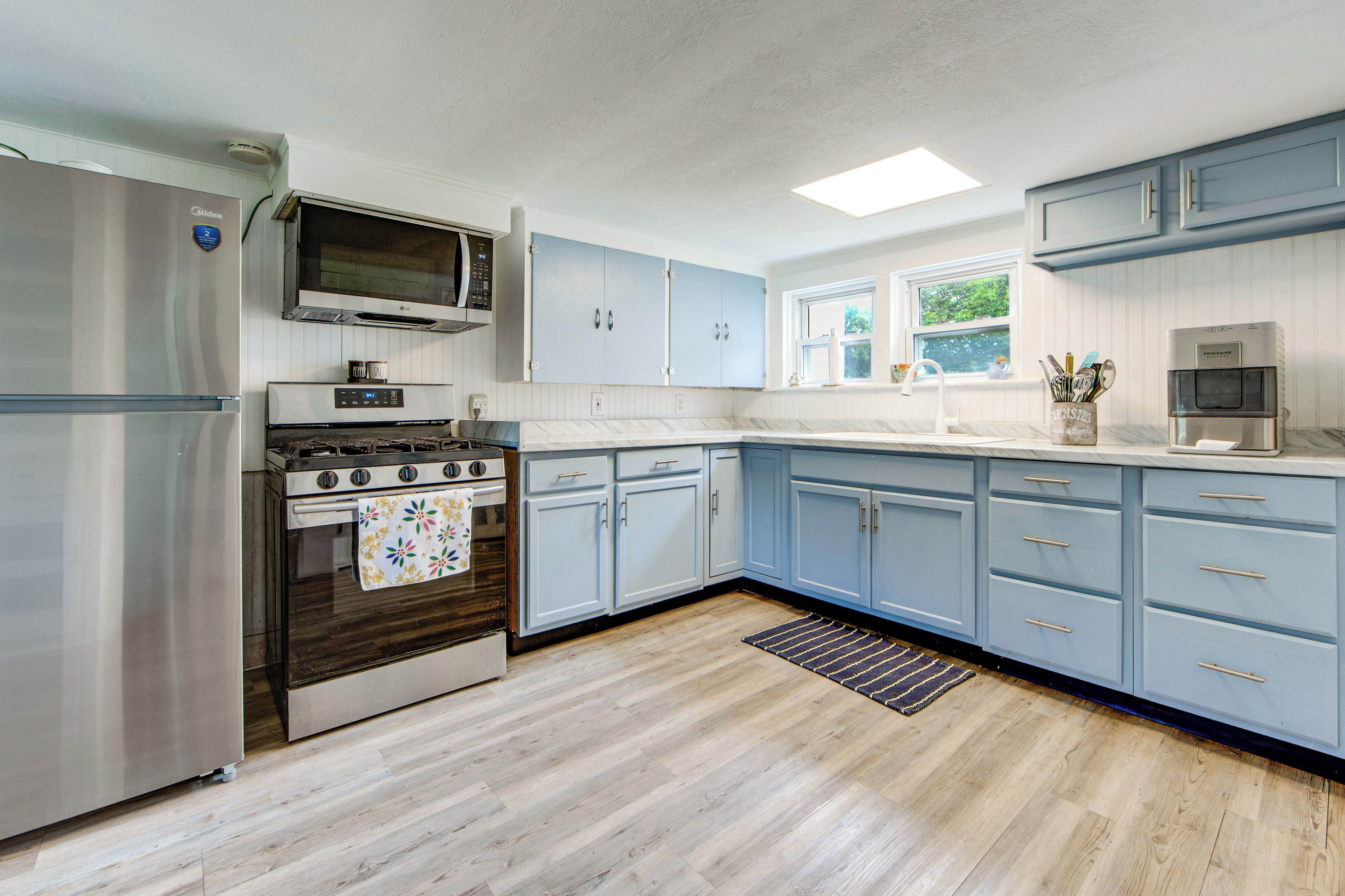 Una cocina moderna con un refrigerador de acero inoxidable, una estufa a gas, un microondas y armarios azul claro.