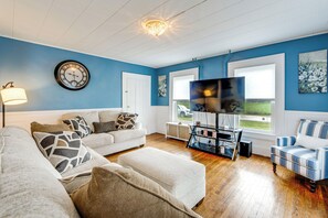 Een woonkamer met een blauwe wand, een klok, een flatscreen televisie en een bank.