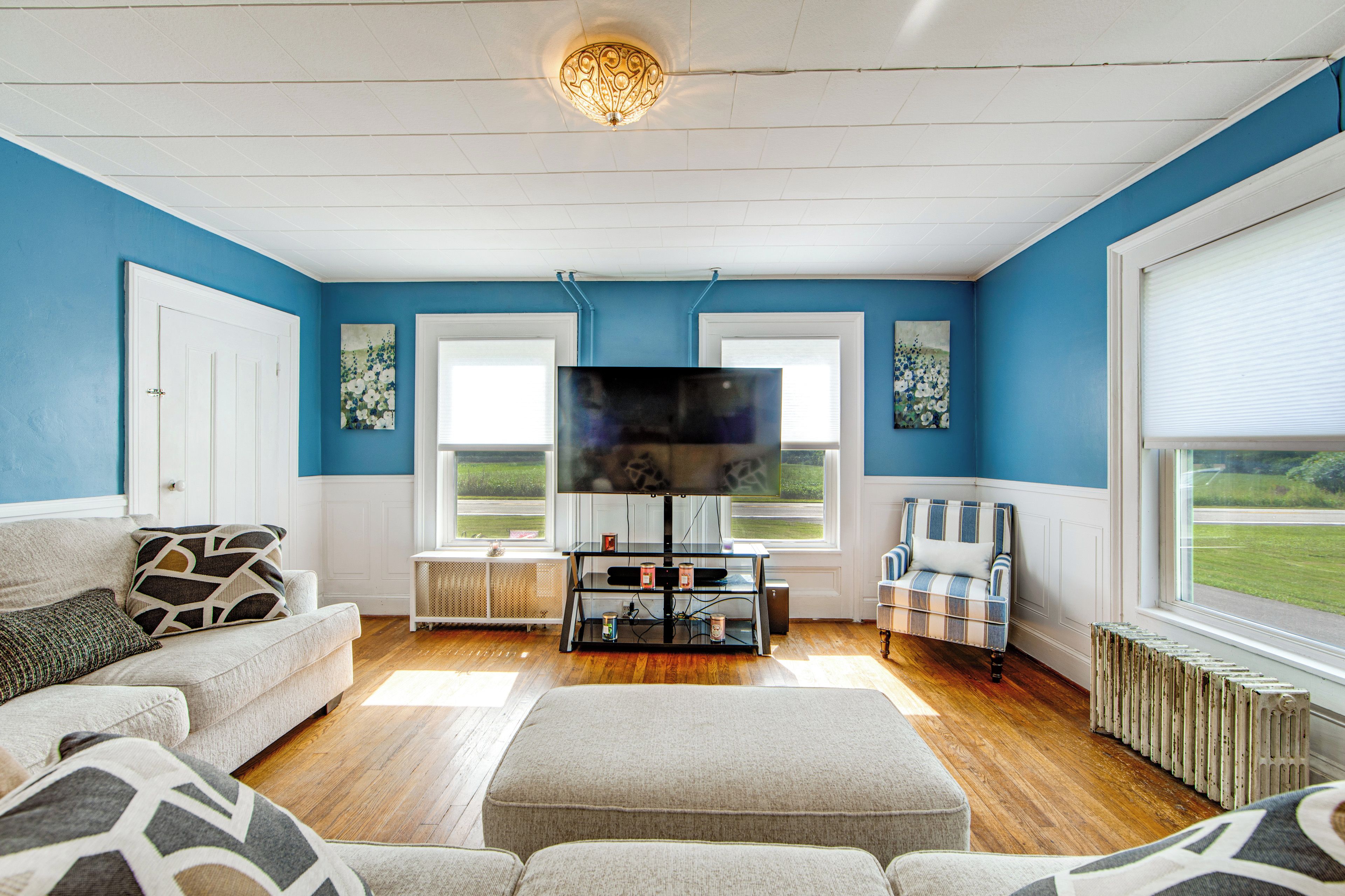 A living room with a television, a sofa, a chair, and a radiator.