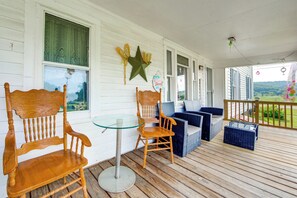 Een overdekt terras met houten stoelen, een glazen tafel en blauwe zachte zitplaatsen.