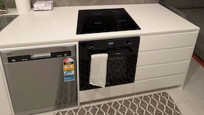 A compact kitchen with a dishwasher, oven, and a built-in stovetop. - Brand new G6 apartment (Gungahlin)