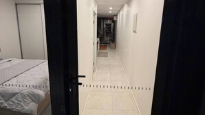 A hotel room with a bed, a door, and a hallway leading to a bathroom. - Brand new G6 apartment (Gungahlin)