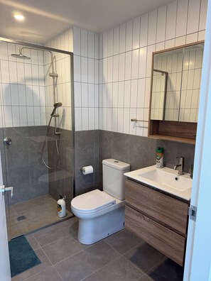 Een moderne badkamer met een douchecabine, een toilet en een wastafel met spiegel.