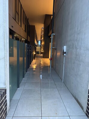 A corridor with a tiled floor, metal railings, and a fire hydrant.
