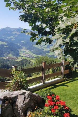 A wooden bench overlooking a scenic landscape with a view of distant mountains and a town. - Hohe salve by Interhome (Hopfgarten im Brixental)