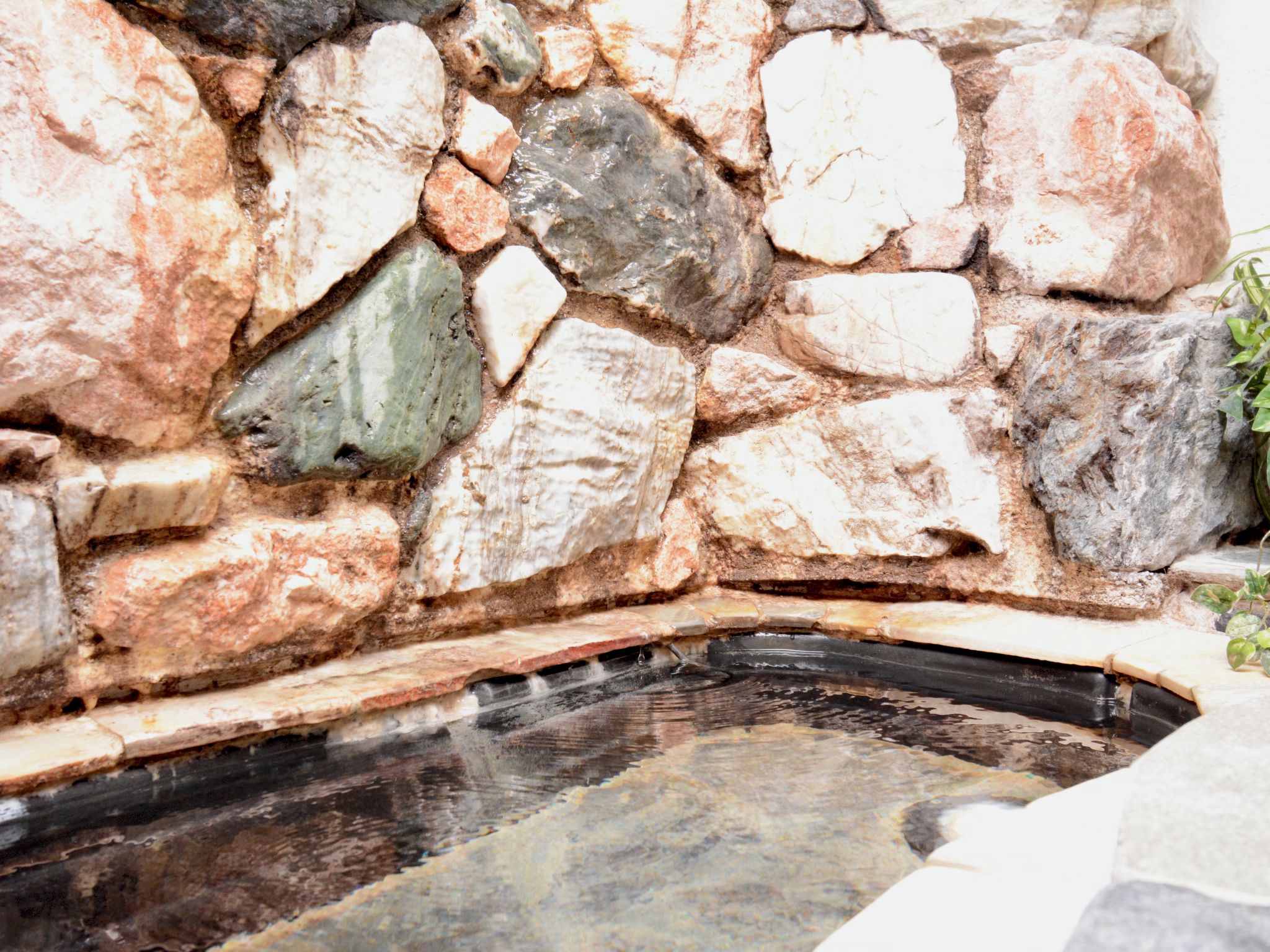 Un mur de pedra amb una piscina rectangular.