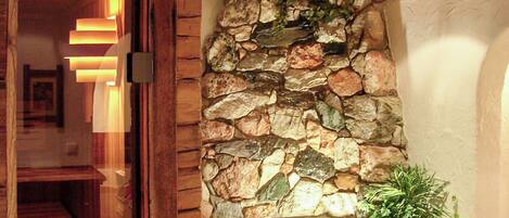 A stone wall with a built-in hot tub and a wooden ceiling structure.