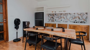 A modern kitchen with a wooden table and chairs, a built-in oven, and a decorative backsplash. - Costa Luna, Modern Mediterranean Villa Near Lancing Beach (Nusa Tenggara Bar.)