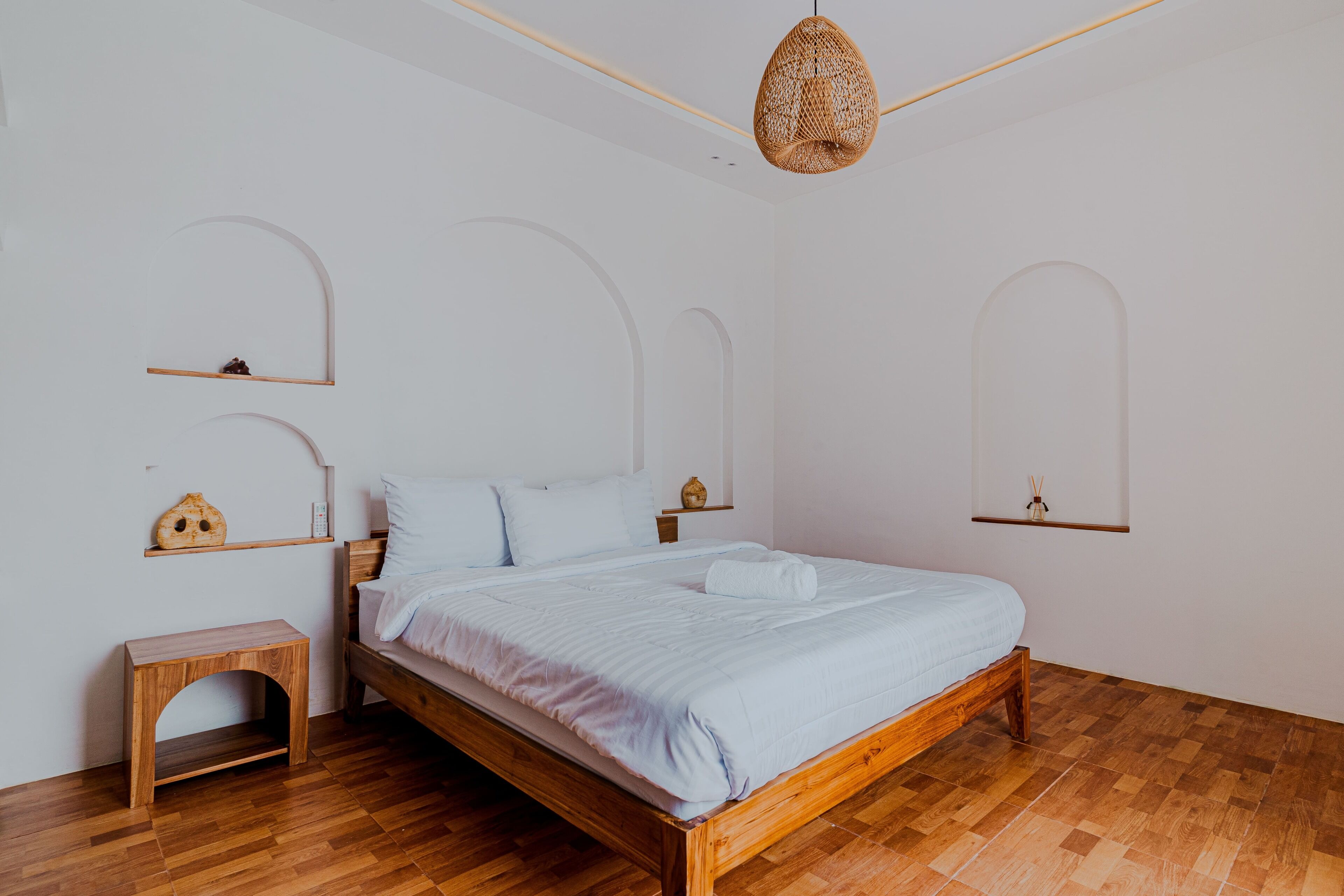 Een slaapkamer met een houten bed, een nachtkastje en een hanglamp.
