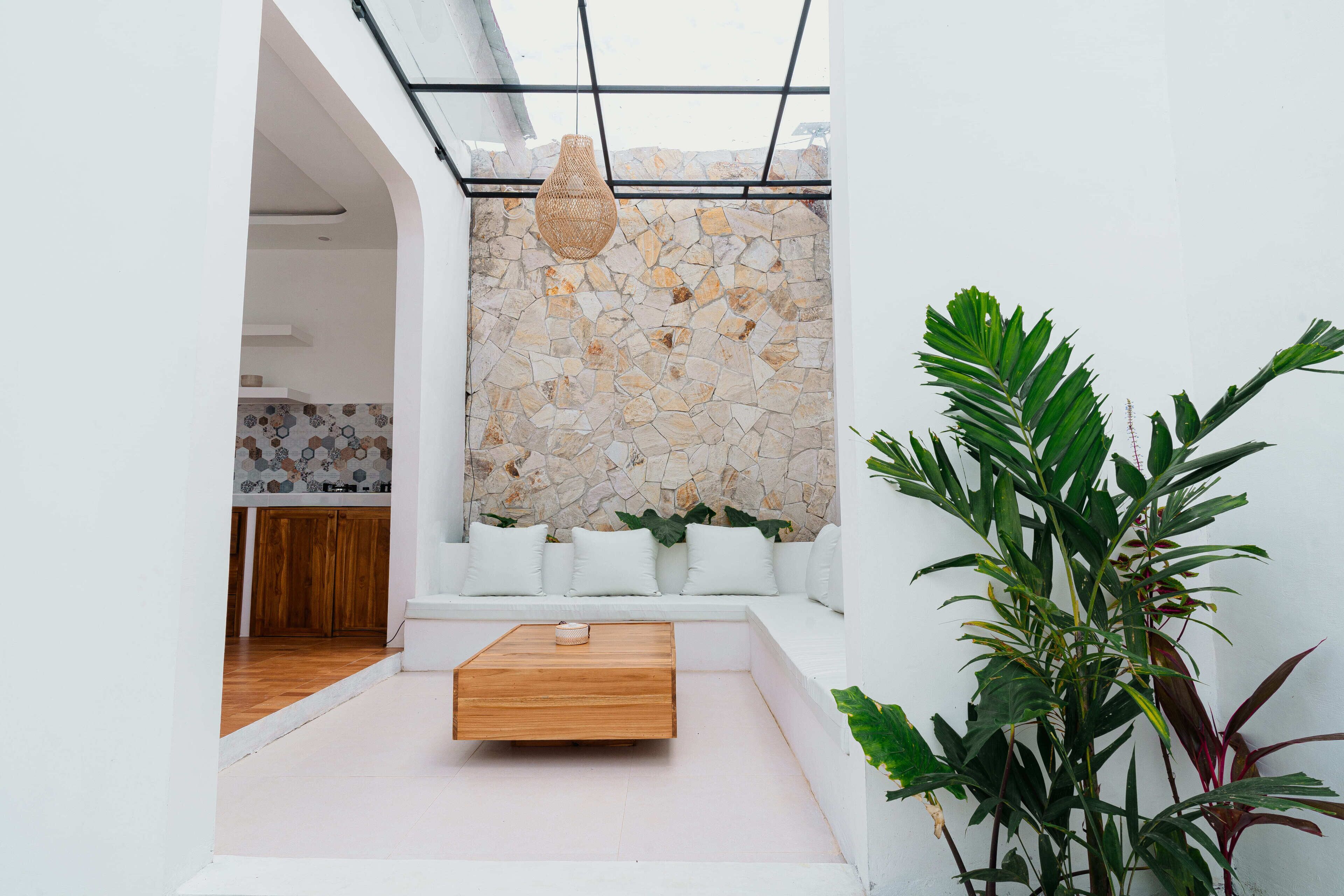 A modern interior with a stone wall, white furniture, and a hanging light fixture.